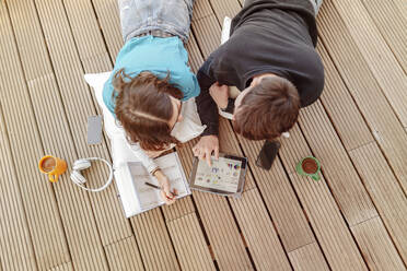 Teenage couple lying on terrace learning together with digital tablet - STDF00223