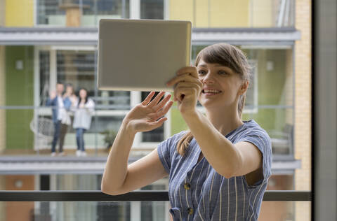 Portrait of smiling young woman using digital tablet for video chat with her neighbours stock photo