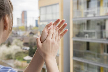 Crop-Ansicht einer in die Hände klatschenden Frau auf einem Balkon - AHSF02459