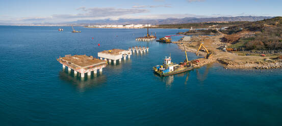 Panoramablick auf Maschinen auf Betonplattformen beim Bau des künftigen LNG-Terminals am Ufer der Bucht von Omisalj, Kroatien - AAEF08036