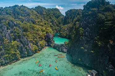 An aerial view of tourists kayaking going in and out in the Small Lagoon to Big Lagoon in Maniloc Island, El Nido, Palawan, Philippines. - AAEF08274