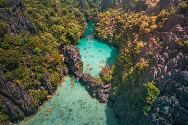 An aerial view of tourists kayaking going in and out in the Small Lagoon to Big Lagoon in Maniloc Island, El Nido, Palawan, Philippines. - AAEF08275