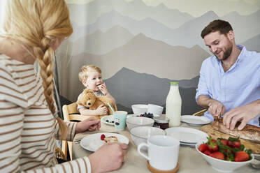 Porträt eines kleinen Jungen, der mit seinen Eltern am Frühstückstisch sitzt - FSF01041