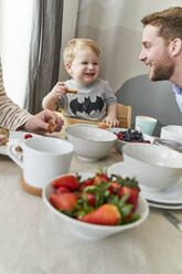 Portrait of happy little boy having fun at breakfast table with his father - FSF01046