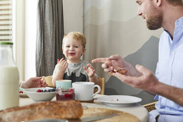 Porträt eines glücklichen kleinen Jungen am Frühstückstisch mit seinen Eltern - FSF01049