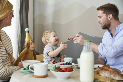 Verschmierter kleiner Junge mit seinen Eltern am Frühstückstisch - FSF01062