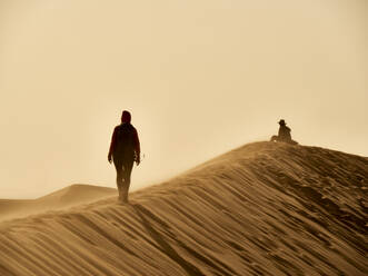 Woman walking on the ridge of a dune in the desert, Walvis Bay, Namibia - VEGF02074