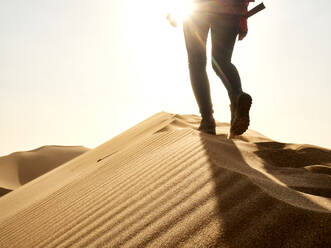 Low section of woman waking on the ridge of a dune in the desert, Walvis Bay, Namibia - VEGF02075