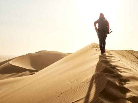 Woman walking on the ridge of a dune in the desert, Walvis Bay, Namibia stock photo