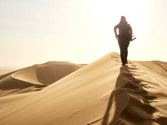 Woman walking on the ridge of a dune in the desert, Walvis Bay, Namibia - VEGF02077