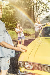 Freunde waschen gelben Oldtimer im Sommer und haben Spaß - SDAHF00796