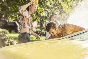 Freunde waschen gelben Oldtimer im Sommer und haben Spaß - SDAHF00798