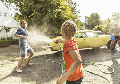 Friends washing yellow vintage car in summer having fun - SDAHF00799