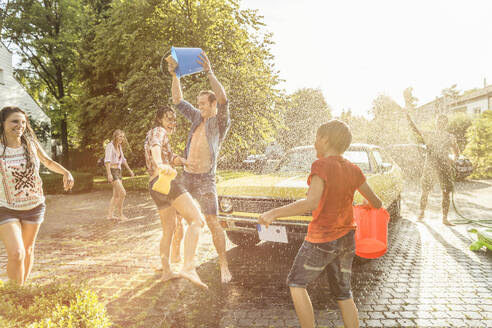 Group of friends washing yellow vintage car in summer having fun - SDAHF00804