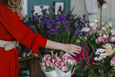 Nahaufnahme einer Frau, die Blumen in einem Blumenladen berührt - OGF00316