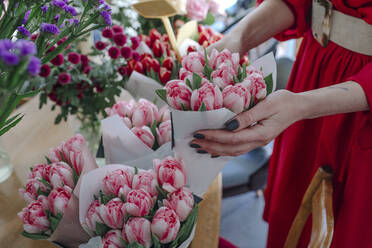 Nahaufnahme einer Frau, die in einem Blumenladen einen Tulpenstrauß auswählt - OGF00333