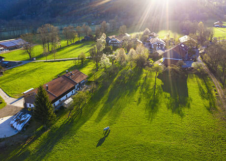 Deutschland, Bayern, Gaissach, Drohnenaufnahme von Sonnenlicht, das Bauernhäuser auf dem Land beleuchtet - SIEF09809