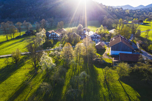 Deutschland, Bayern, Gaissach, Drohnenaufnahme von Sonnenlicht, das Bauernhäuser auf dem Land beleuchtet - SIEF09810