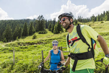Glückliches Paar mit Mountainbikes auf einer Wiese in den Bergen, Achenkirch, Österreich - SDAHF00819