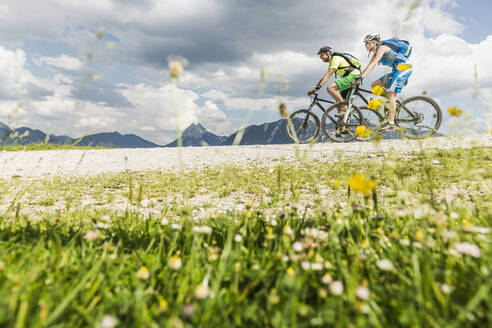 Couple mountainbiking on gravel path in the mountains, Achenkirch, Austria - SDAHF00826