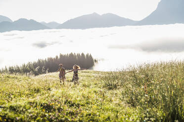 Zwei Freundinnen laufen auf einer Wiese in den Bergen, Achenkirch, Österreich - SDAHF00852