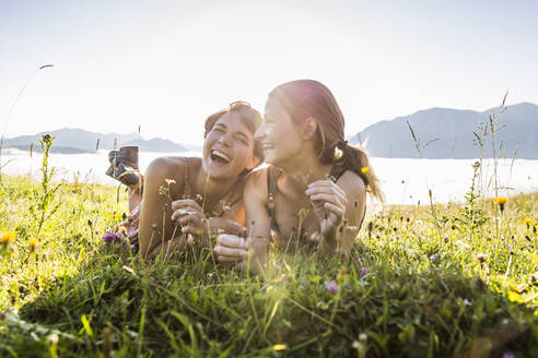 Two happy female friends lying on a meadow in the mountains, Achenkirch, Austria - SDAHF00856