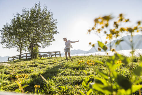 Unbeschwerte Frau tanzt auf einer Wiese in den Bergen, Achenkirch, Österreich - SDAHF00858