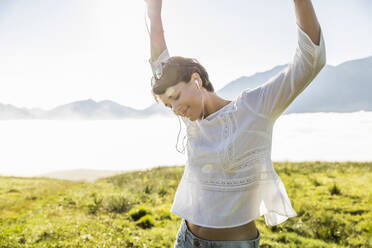 Happy woman listening to music on a meadow in the mountains, Achenkirch, Austria - SDAHF00859