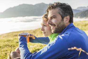 Couple sitting on a meadow in the mountains at dawn, Achenkirch, Austria - SDAHF00885