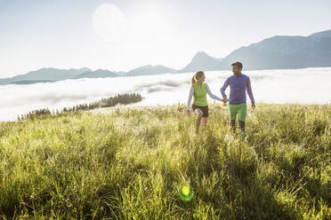 Pärchen beim Wandern auf einer Bergwiese bei Sonnenaufgang, Achenkirch, Österreich - SDAHF00889