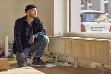 Mann renoviert Ladenlokal, kniend auf dem Boden - MCF00791