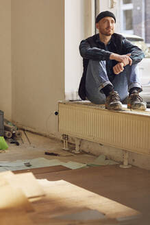 Mann renoviert Ladenlokal, sitzt auf der Fensterbank - MCF00797