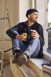 Mann renoviert Ladenlokal, sitzt auf der Fensterbank und trinkt Kaffee - MCF00806
