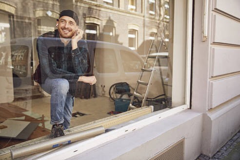 Mann renoviert Ladenlokal, benutzt Kopfhörer am Fenster - MCF00812