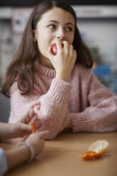 Girl in classroom during break time eating an apple - PWF00053