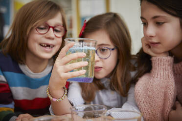 Drei Kinder betrachten eine Flüssigkeit in einer Chemiestunde - PWF00073