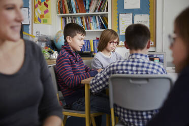 Gruppe von Kindern hinter einem Lehrer in einem Klassenzimmer während einer Unterrichtsstunde - PWF00081