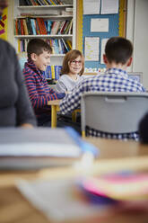 Gruppe von Kindern in einem Klassenzimmer während einer Unterrichtsstunde, die miteinander interagieren - PWF00082