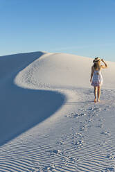 Eine Frau geht entlang der S-Kurve eines Dünenkamms im White Sands National Park, New Mexico, Vereinigte Staaten von Amerika, Nordamerika - RHPLF14635