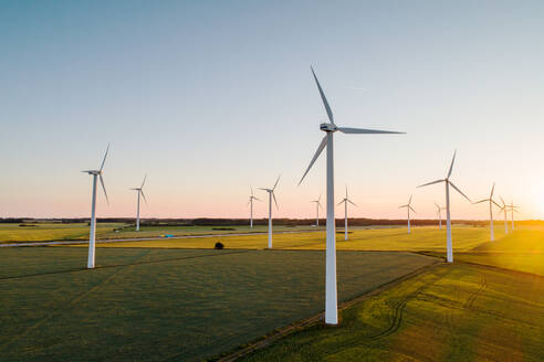Wind turbines on grassy land against clear sky - MASF17897
