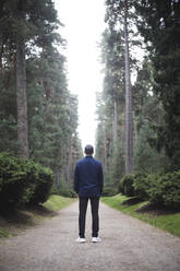 Rear view of man standing on footpath against sky - MASF17910