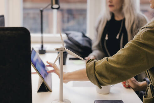 Geschäftskollegen diskutieren über Windenergie auf einem digitalen Tablet am Bürotisch - MASF17931