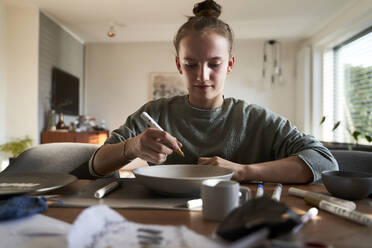 Mädchen zu Hause bemalt Schüssel mit Porzellanfarbe - AUF00348