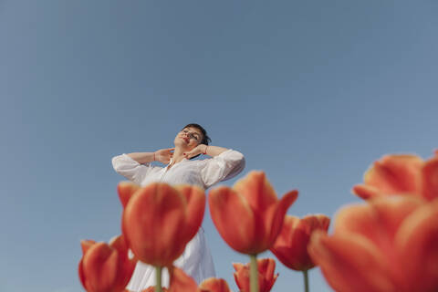 Lächelnde Frau entspannt sich in einem Tulpenfeld, lizenzfreies Stockfoto