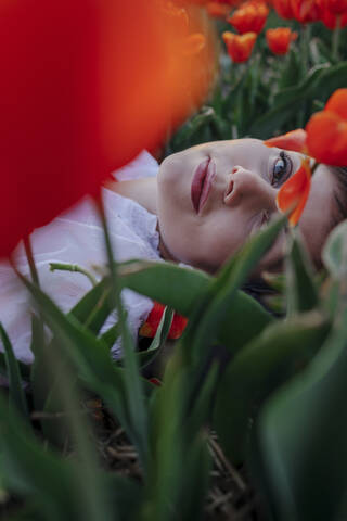 Portrait of woman lying between tulips stock photo