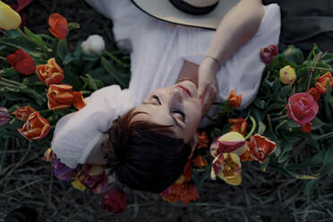 Porträt einer auf dem Boden liegenden Frau zwischen Tulpen - OGF00370