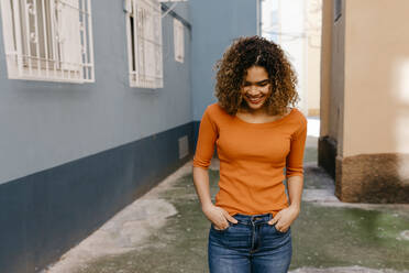 Portrait of smiling woman wearing orange pullover - TCEF00546