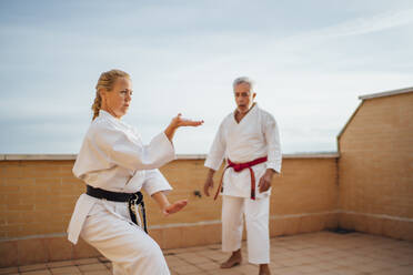 Frau mit Lehrer beim Karatetraining auf der Terrasse - OCMF01202