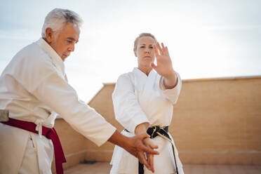 Woman with teacher during karate training on terrace - OCMF01204