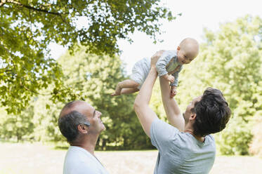 Älterer Mann verbringt Zeit mit seinem erwachsenen Sohn und seiner Enkelin in einem Park - DIGF10240